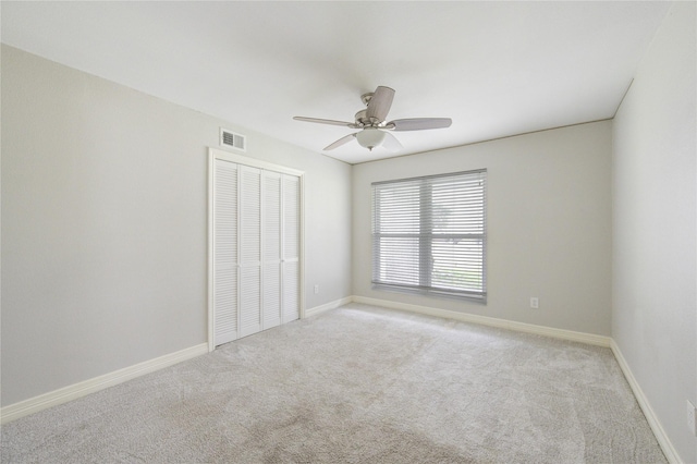 unfurnished bedroom with a ceiling fan, baseboards, visible vents, a closet, and light carpet