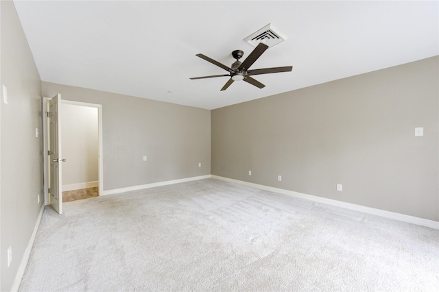 spare room with light colored carpet, a ceiling fan, visible vents, and baseboards