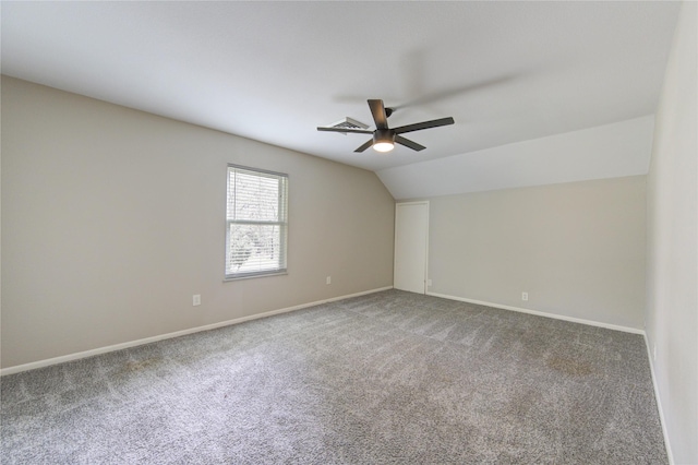 carpeted empty room with vaulted ceiling, a ceiling fan, baseboards, and visible vents