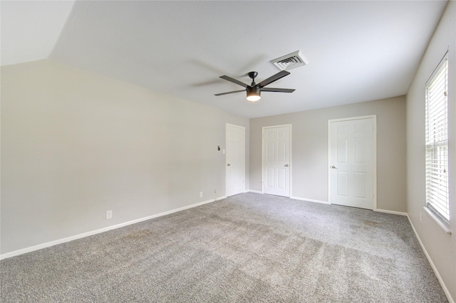 unfurnished bedroom featuring carpet, multiple windows, baseboards, and visible vents