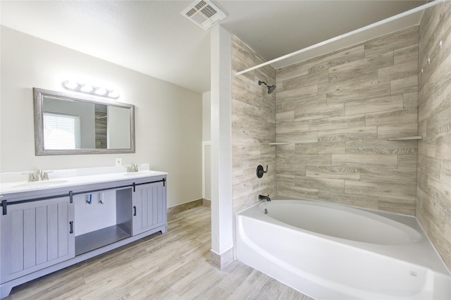 full bathroom with a sink, visible vents, shower / bath combination, and wood finished floors