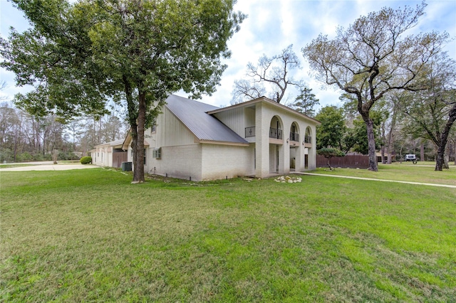 view of front of home featuring driveway, brick siding, central AC, and a front yard