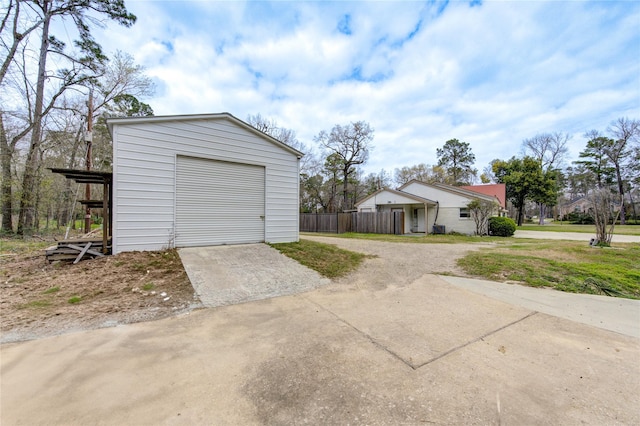 garage with concrete driveway and fence