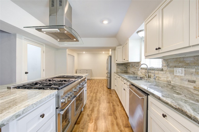 kitchen with island exhaust hood, a sink, stainless steel appliances, white cabinets, and light wood-type flooring