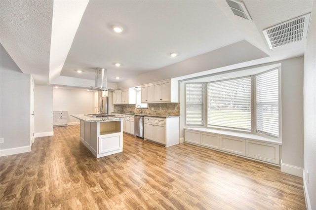 kitchen with visible vents, backsplash, appliances with stainless steel finishes, island exhaust hood, and light wood-style floors