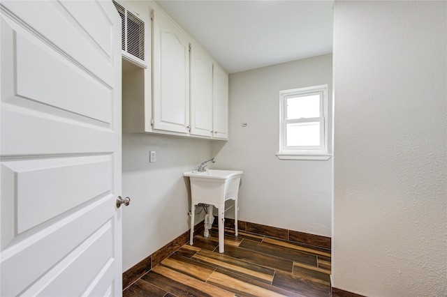 washroom with wood finish floors, visible vents, and baseboards