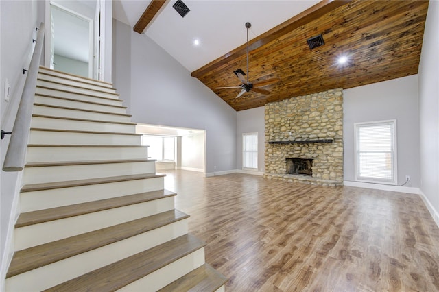 unfurnished living room with wood finished floors, a ceiling fan, baseboards, high vaulted ceiling, and stairs