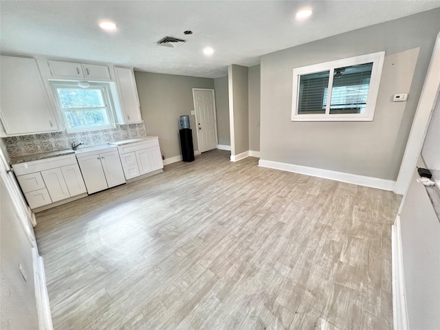 kitchen with decorative backsplash, baseboards, visible vents, and light wood-type flooring