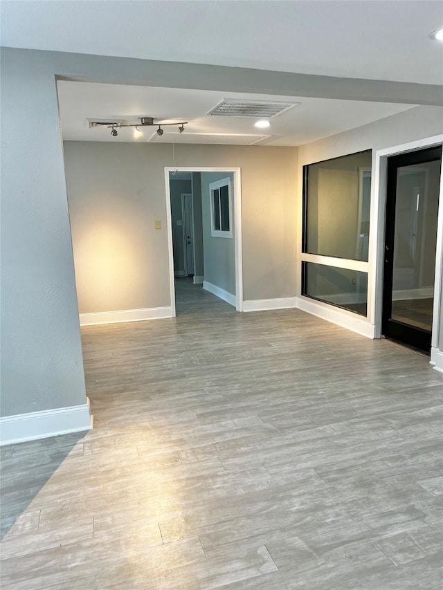 spare room with visible vents, track lighting, baseboards, and wood finished floors