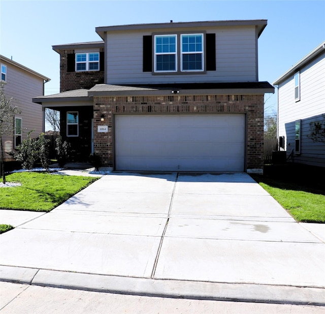 traditional-style home with brick siding, an attached garage, concrete driveway, and a front lawn