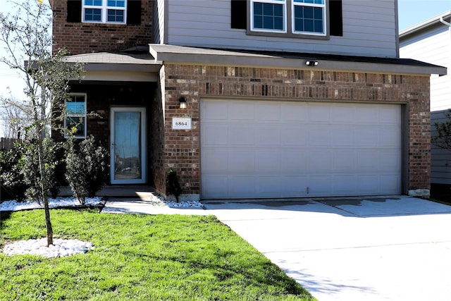 property entrance featuring brick siding, an attached garage, and driveway