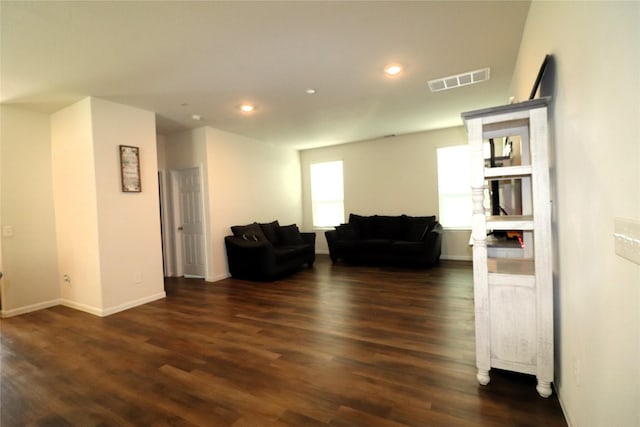 living area with dark wood finished floors, visible vents, recessed lighting, and baseboards