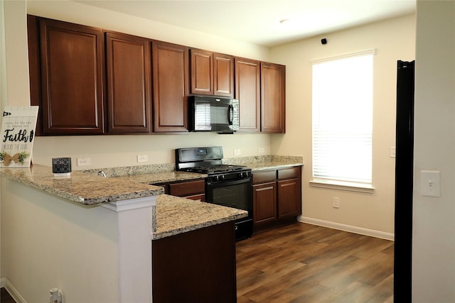 kitchen featuring light stone counters, baseboards, dark wood finished floors, a peninsula, and black appliances