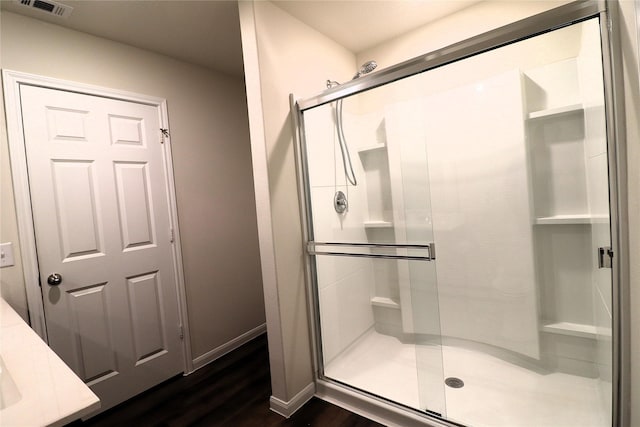 full bathroom featuring visible vents, wood finished floors, baseboards, and a stall shower