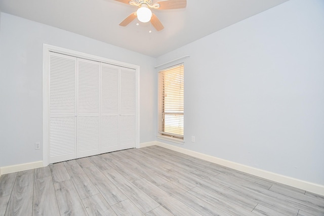 unfurnished bedroom featuring a closet, baseboards, light wood finished floors, and ceiling fan