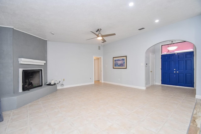 unfurnished living room with visible vents, baseboards, ceiling fan, a fireplace, and arched walkways