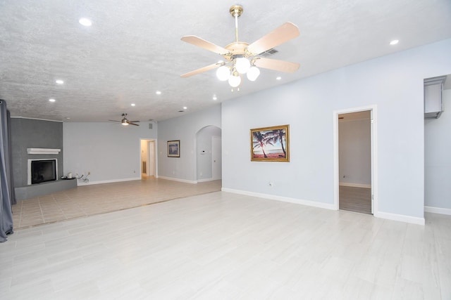 unfurnished living room featuring visible vents, a large fireplace, baseboards, recessed lighting, and arched walkways