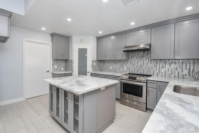 kitchen featuring gray cabinetry, under cabinet range hood, a sink, stainless steel electric range oven, and light stone countertops