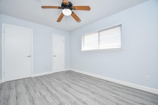 empty room with baseboards, a ceiling fan, and light wood finished floors