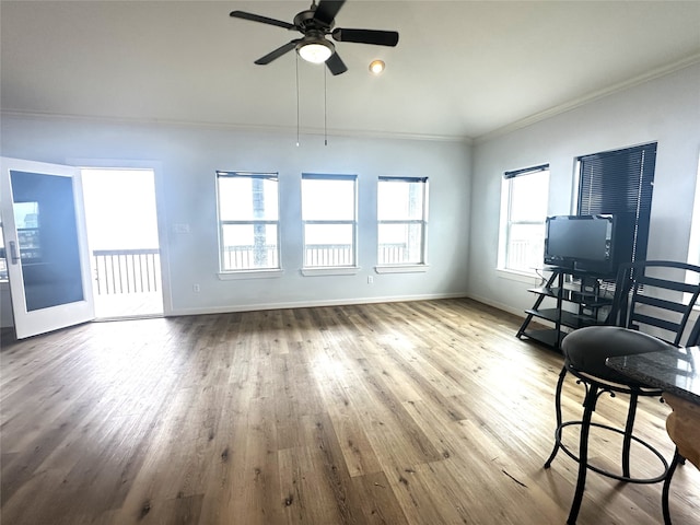 unfurnished living room with ornamental molding, ceiling fan, baseboards, and wood finished floors