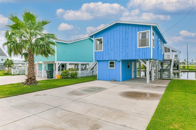 beach home with stairs, a front lawn, a carport, and driveway