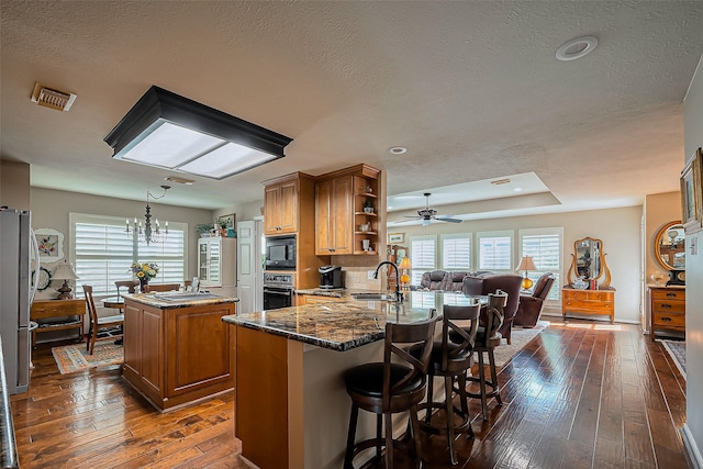 kitchen with a sink, a center island, brown cabinets, black appliances, and open shelves