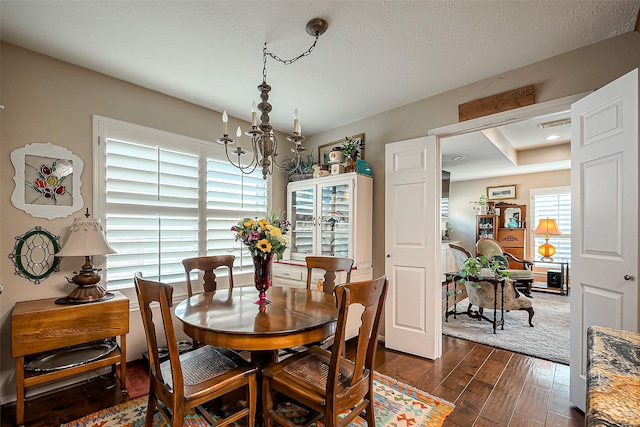 dining area featuring a chandelier, a textured ceiling, and dark wood-style floors