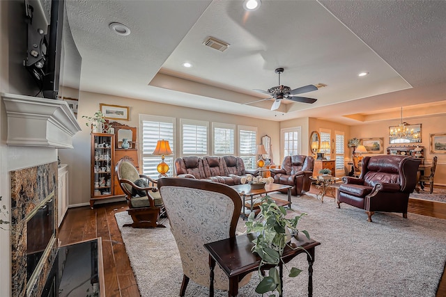 living room with visible vents, a textured ceiling, a fireplace, a raised ceiling, and dark wood-style flooring