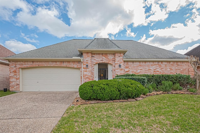 french country inspired facade featuring brick siding, concrete driveway, and a shingled roof