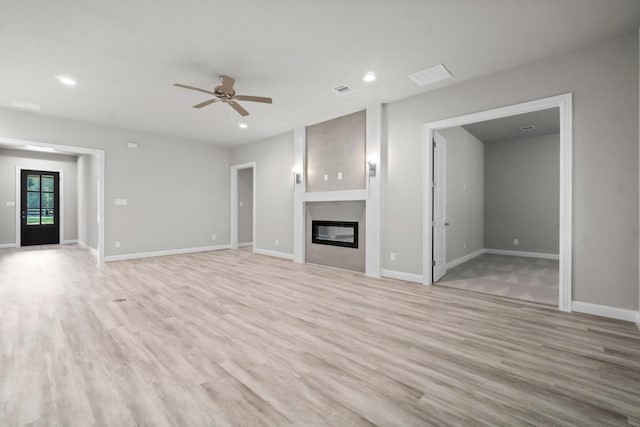 unfurnished living room with a glass covered fireplace, light wood-style flooring, and baseboards