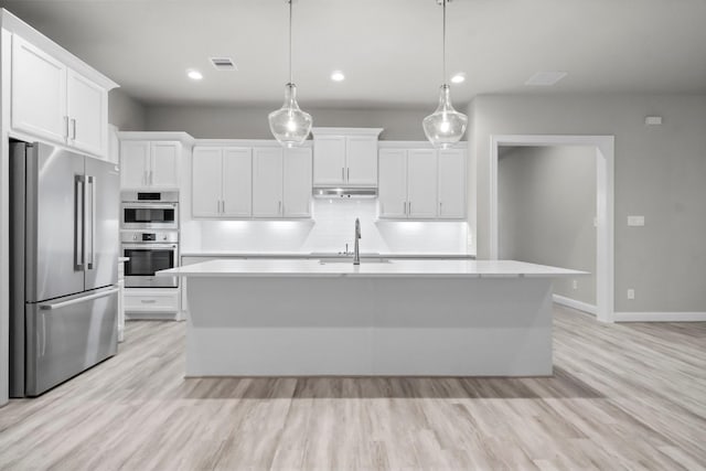 kitchen with a sink, light countertops, under cabinet range hood, and stainless steel appliances