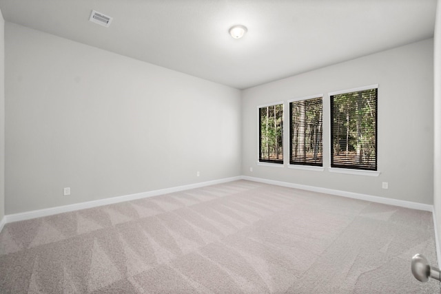 unfurnished room with light carpet, visible vents, and baseboards