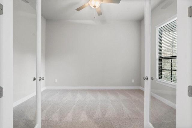 carpeted spare room with a ceiling fan, french doors, and baseboards