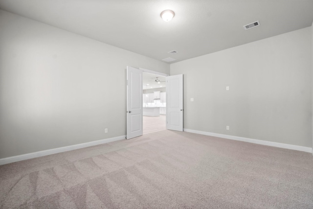 empty room with visible vents, baseboards, and light colored carpet