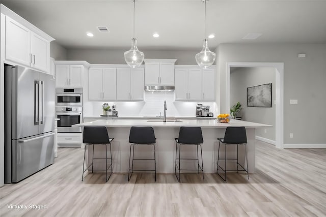 kitchen featuring a sink, decorative backsplash, light countertops, stainless steel appliances, and under cabinet range hood