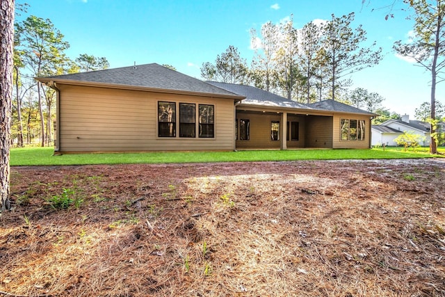 rear view of property featuring a lawn and a shingled roof