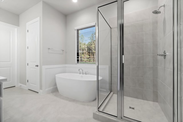 bathroom featuring a freestanding bath, a stall shower, and wainscoting