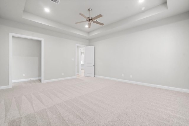 unfurnished bedroom with a tray ceiling, baseboards, and light carpet