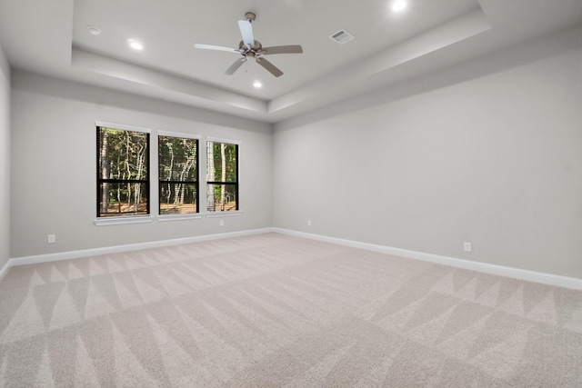 empty room featuring a raised ceiling, baseboards, visible vents, and light carpet