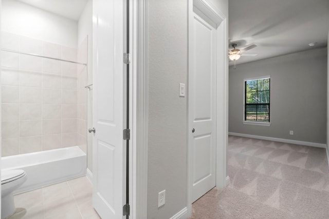 bathroom with a ceiling fan, baseboards, bathing tub / shower combination, tile patterned floors, and toilet