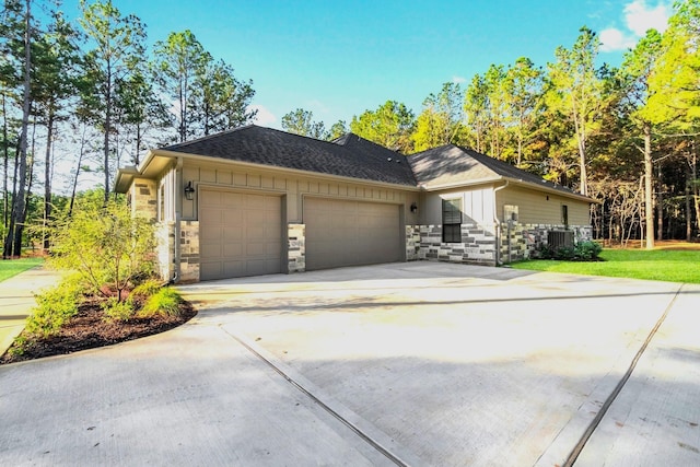 view of front of property featuring an attached garage, concrete driveway, stone siding, central air condition unit, and board and batten siding