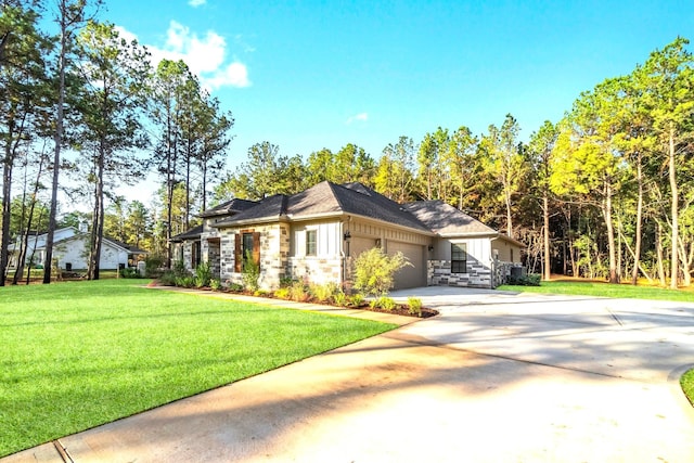 view of front of property featuring stone siding, a front yard, concrete driveway, and an attached garage