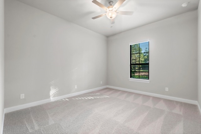 carpeted spare room with baseboards and a ceiling fan