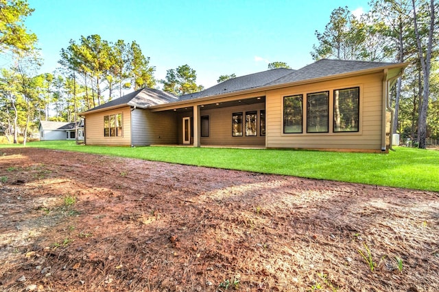 back of house with a yard and roof with shingles