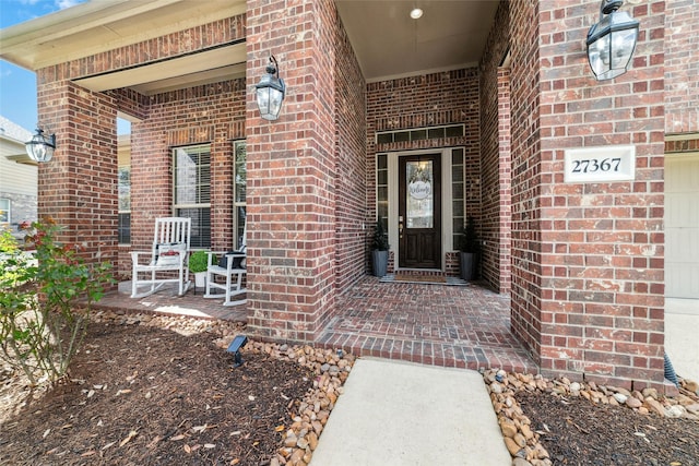 entrance to property featuring brick siding and covered porch