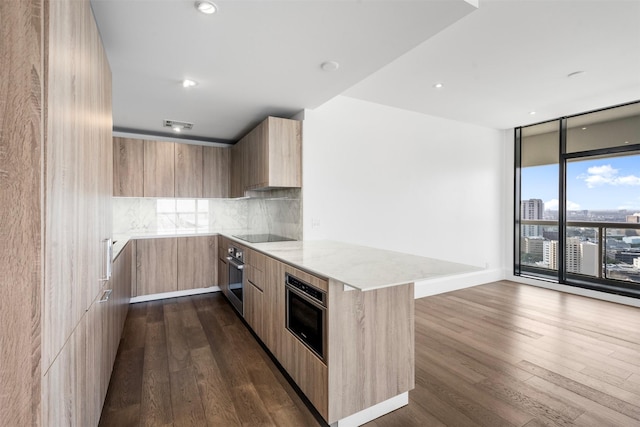 kitchen featuring tasteful backsplash, light brown cabinets, oven, floor to ceiling windows, and modern cabinets