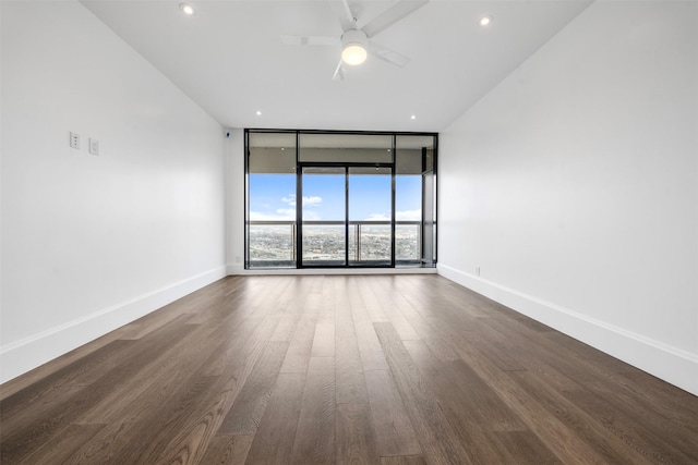 spare room with a ceiling fan, expansive windows, wood finished floors, recessed lighting, and baseboards