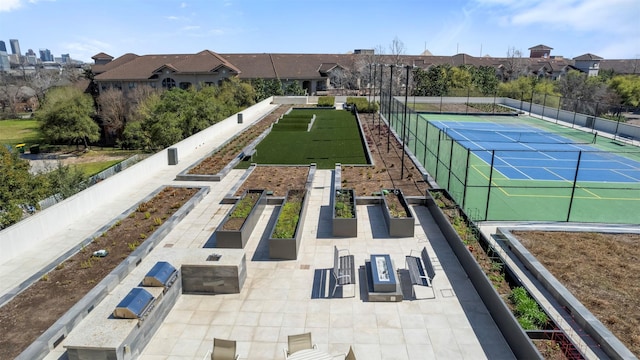 surrounding community with a tennis court, a vegetable garden, and fence