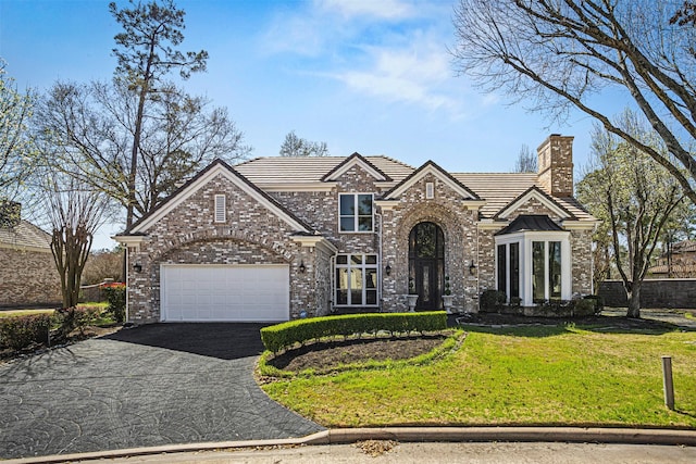 view of front facade with a front yard, aphalt driveway, a chimney, a tile roof, and brick siding