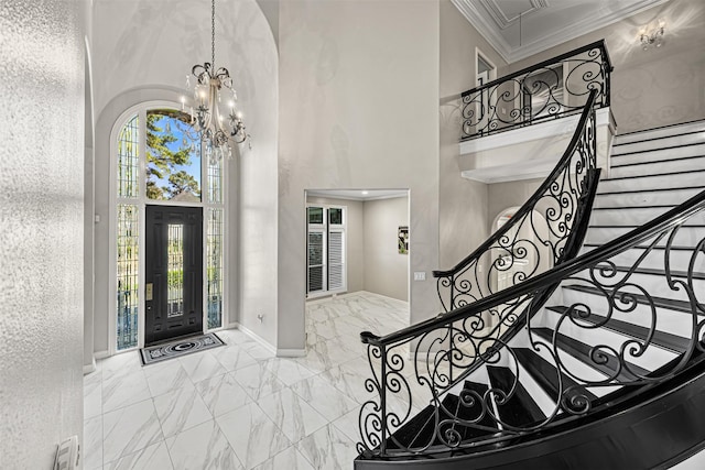 entrance foyer with baseboards, ornamental molding, an inviting chandelier, a towering ceiling, and marble finish floor